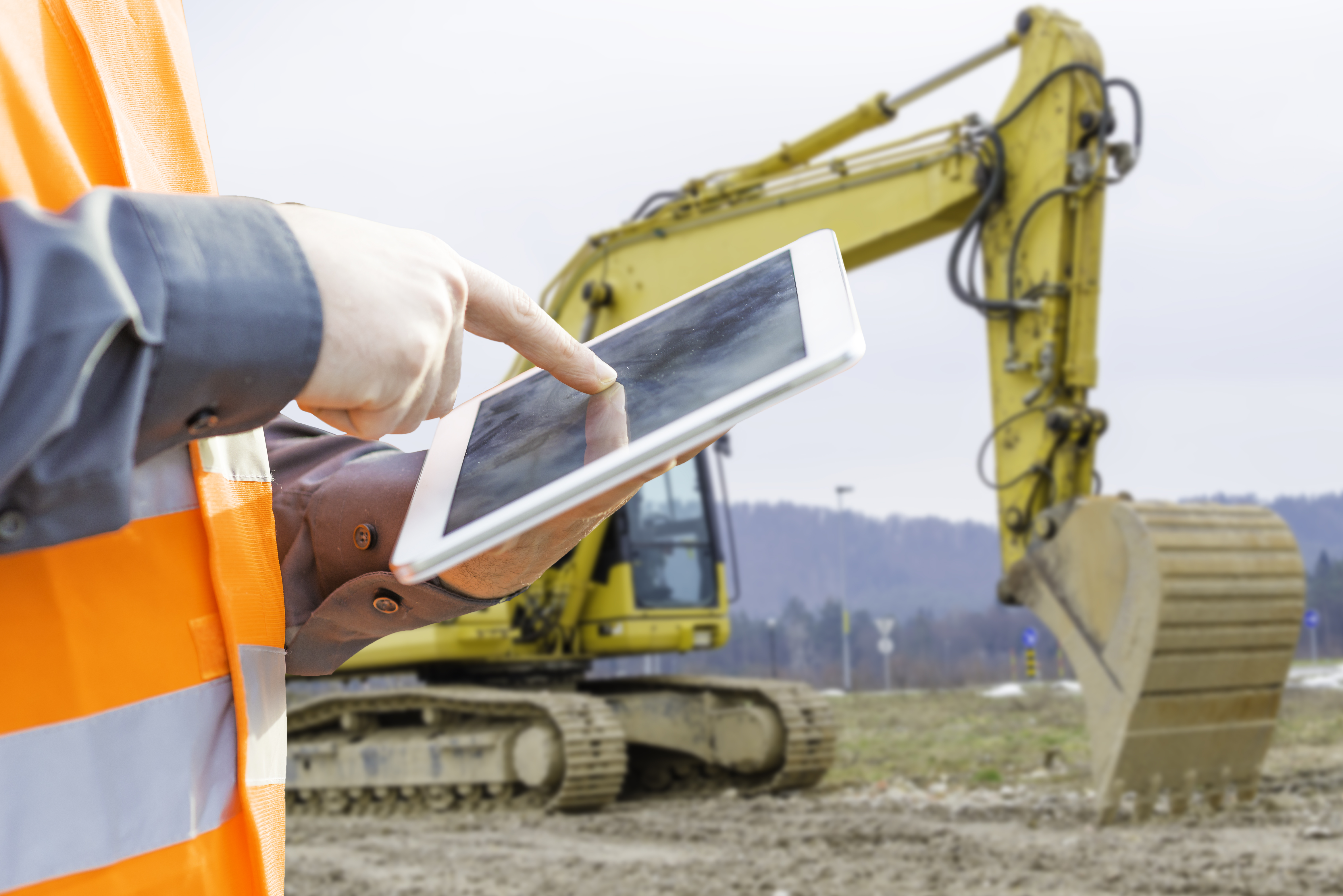 man on construction site looking at a tablet